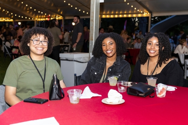 a group of three young people at a table smiling