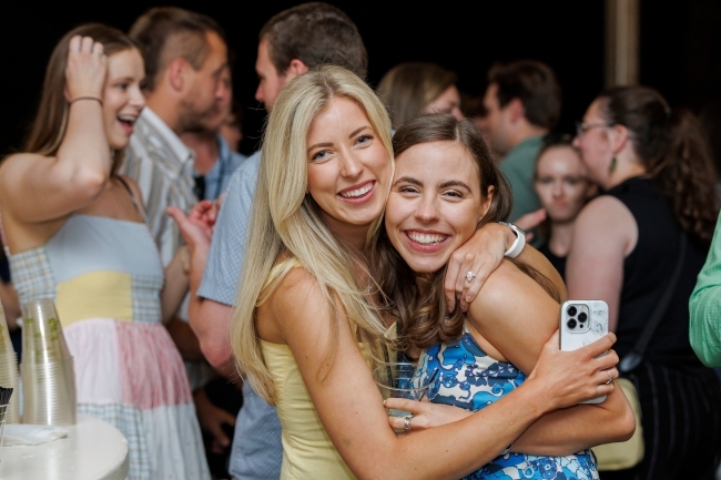 two young women embrace and smile