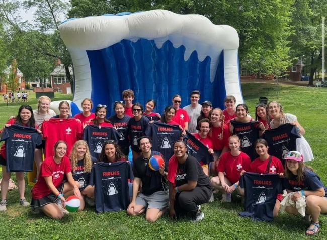 a group of students smile together in front of an inflatable wave