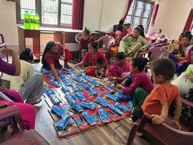 a group of people sit around a mat of supplies