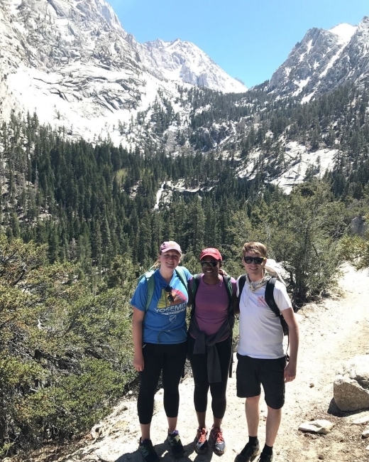 three young people stand together on the side of a mountain