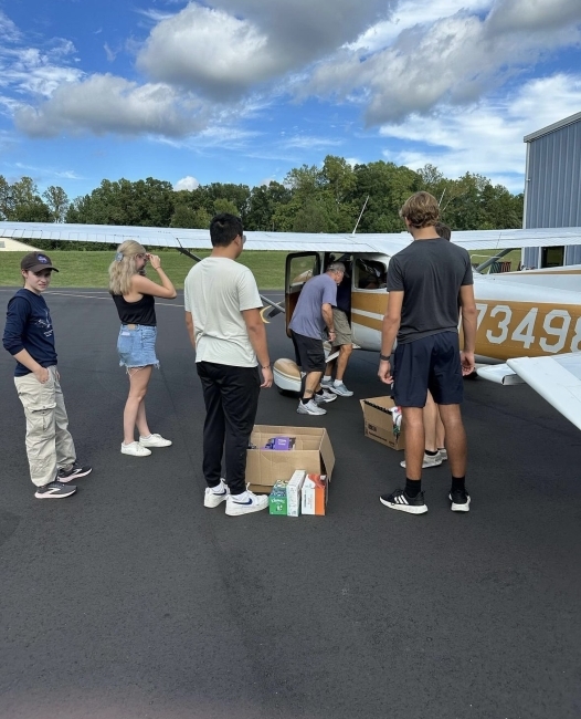 a group of people put boxes on an airplane