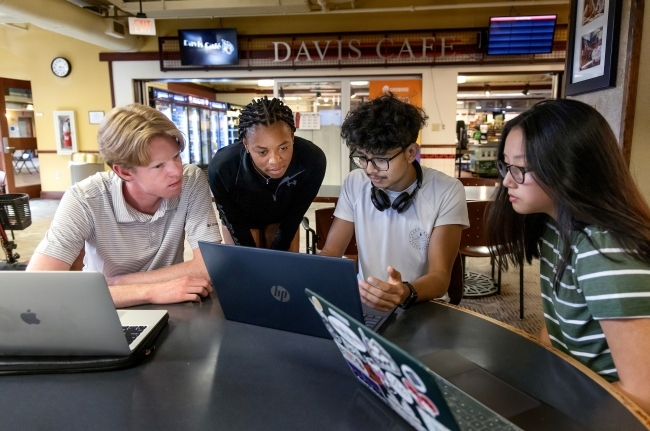 Students gathered around laptops in the student union