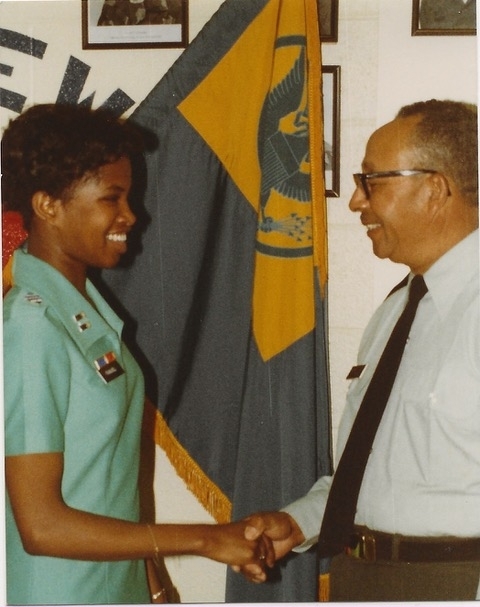 a young Black woman shakes the hand of an older man