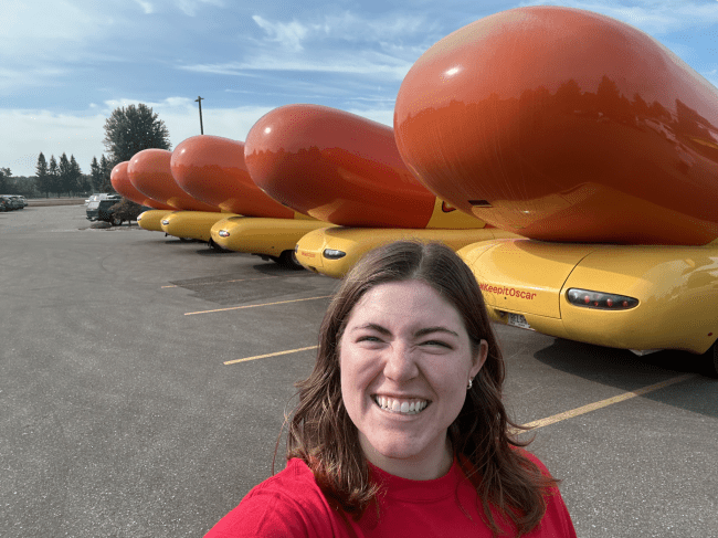 Emily Schmidtt '23 takes a selfie in front of lined-up Weinermobiles