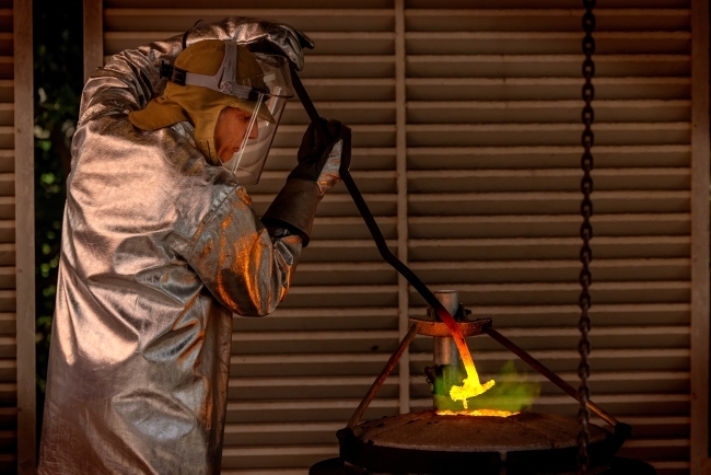 an artist leans over a bronzing project in a studio