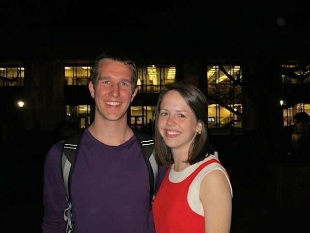 a young couple standing in front of a library at night