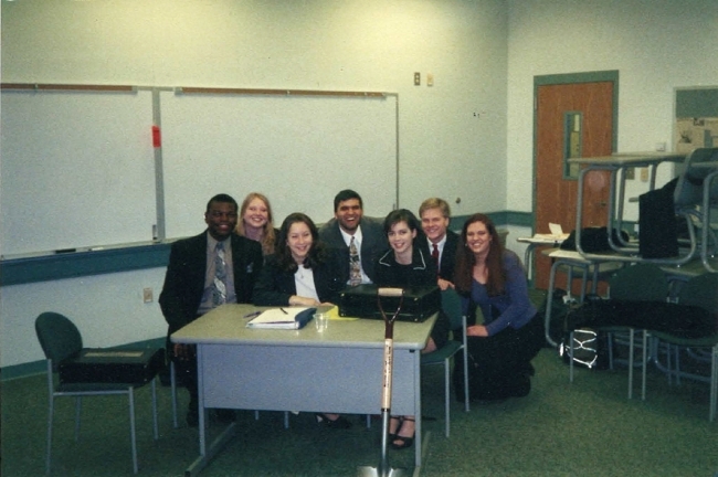 a group of young people sitting together around a desk in a classroom