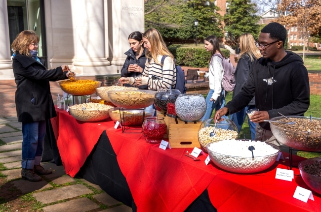 a group of students stand over a table with trail mix ingredients