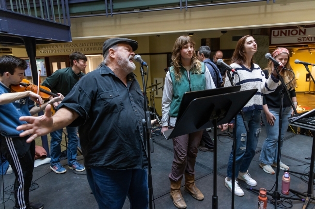 a group of faculty, staff and students perform in a band together on a stage