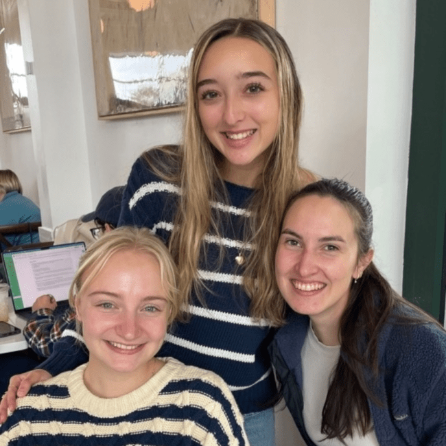 a group of three young women sitting around a table together