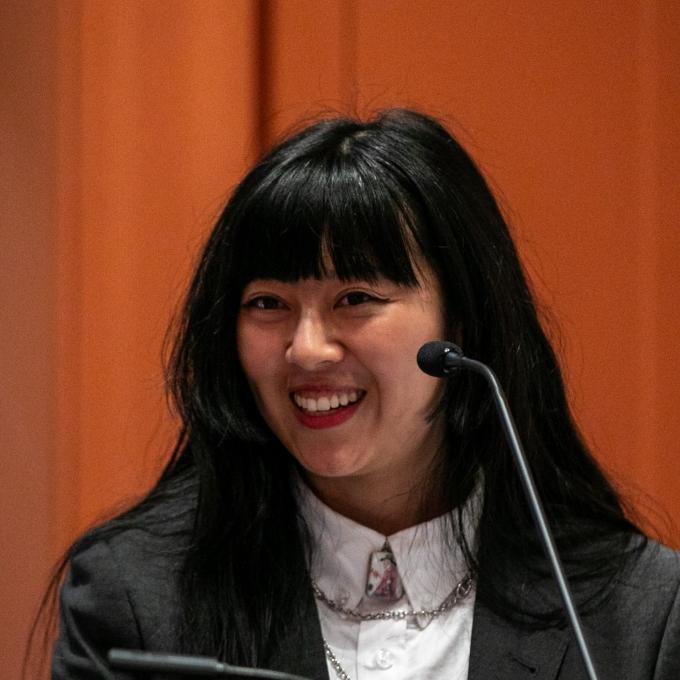 a young Asian woman speaking at a podium and smiling