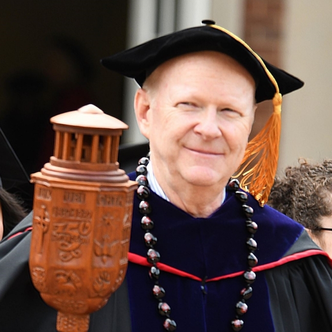 Dan Boye holding academic mace made of ornate carved wood