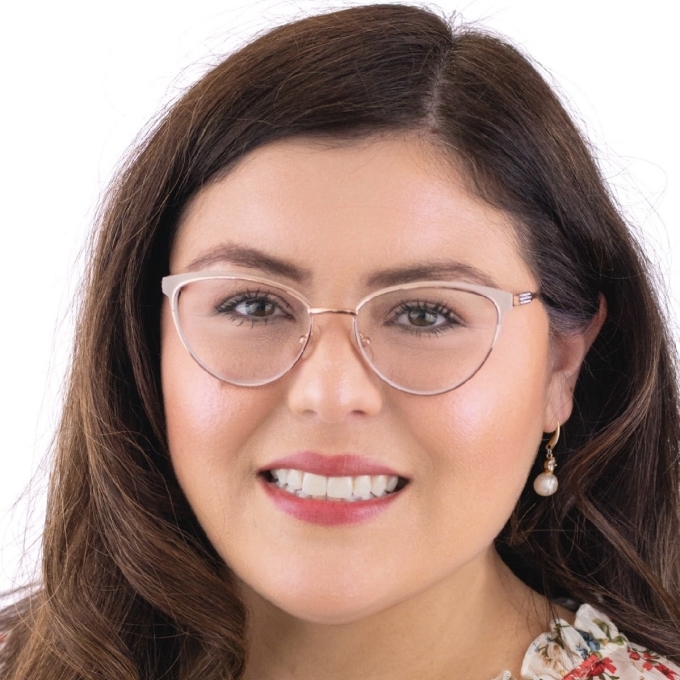 a young woman with dark brown hair wearing a floral top and glasses