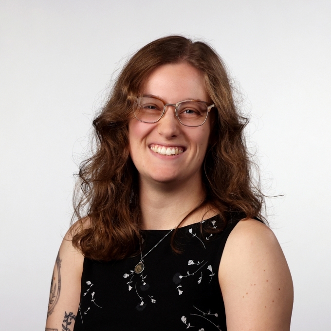 a young white woman with curly brown hair and glasses