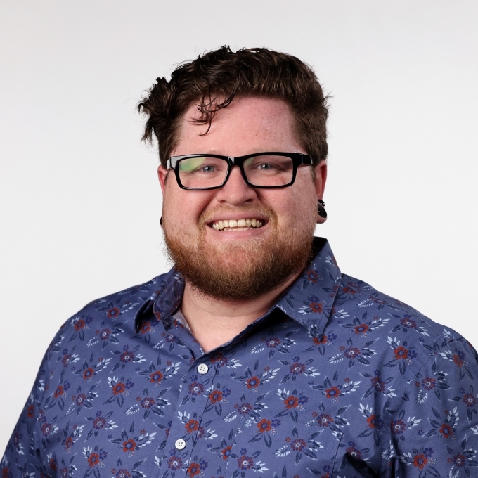 a young white man with glasses and a colorful collared shirt