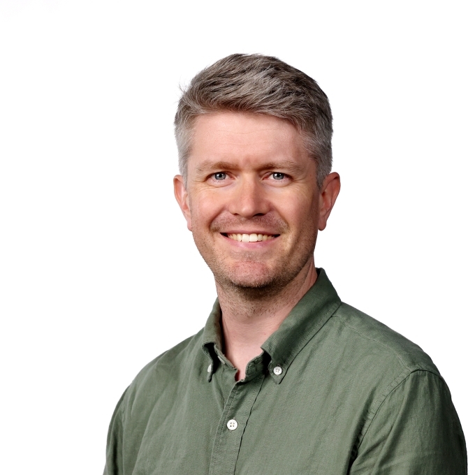 a middle aged white man wearing a green collared top