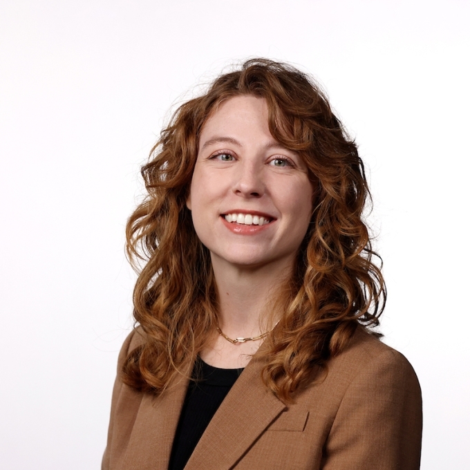 a young white woman with red hair wearing a brown blazer