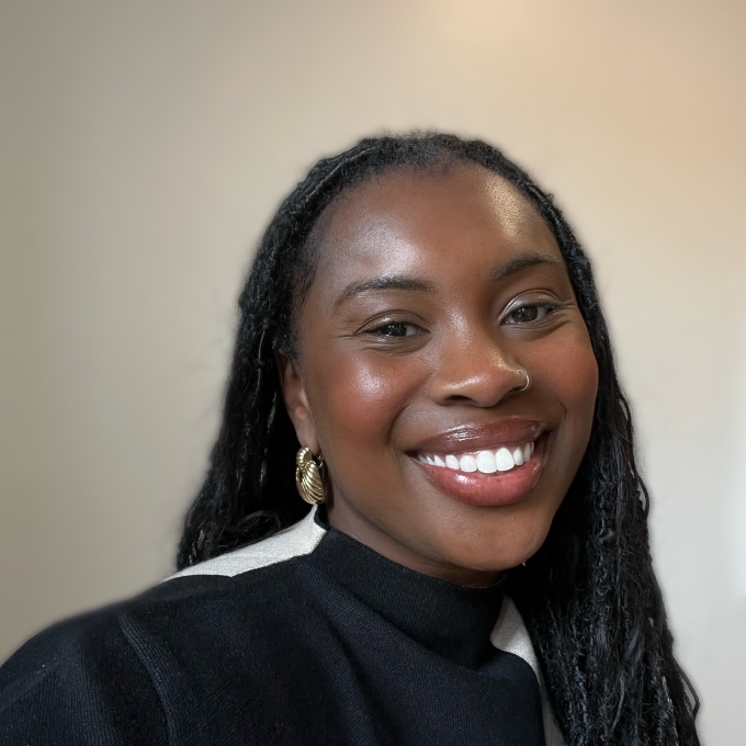 a young Black woman wearing a striped sweater and gold earrings