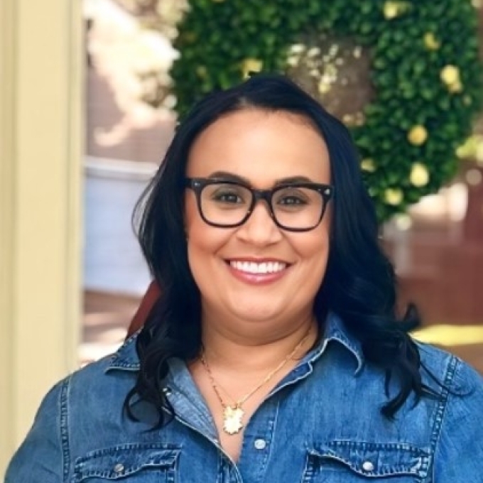 a woman wearing black glasses with dark hair and denim shirt