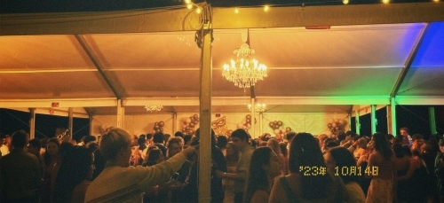 a tent covered in string lights at night and young people dancing underneath it