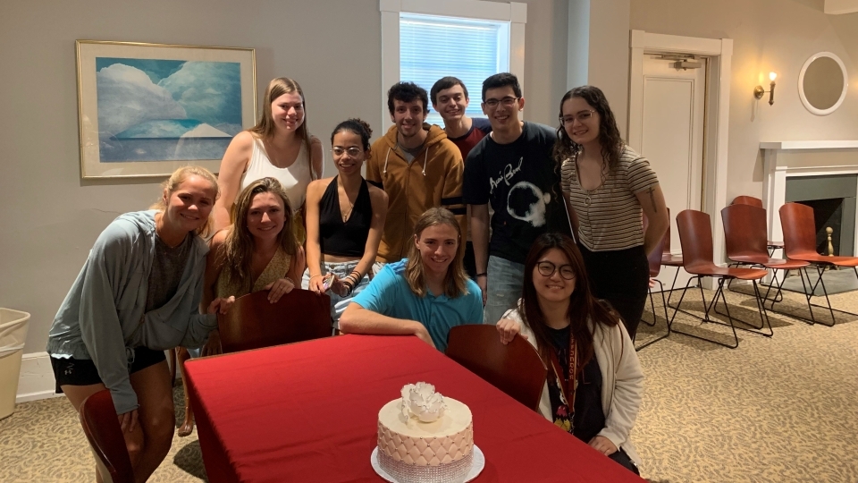 Students pose around a wedding cake