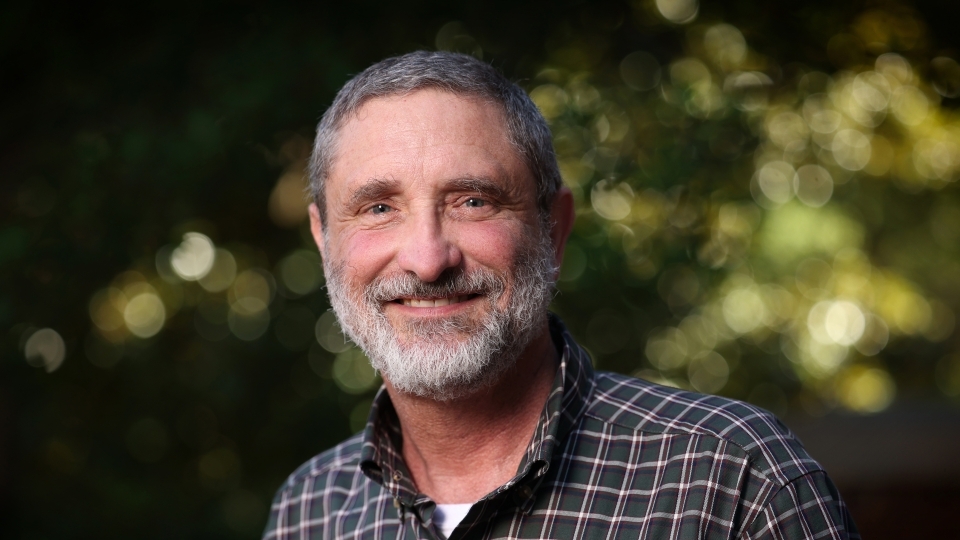 a white man smiles and wears a flannel shirt