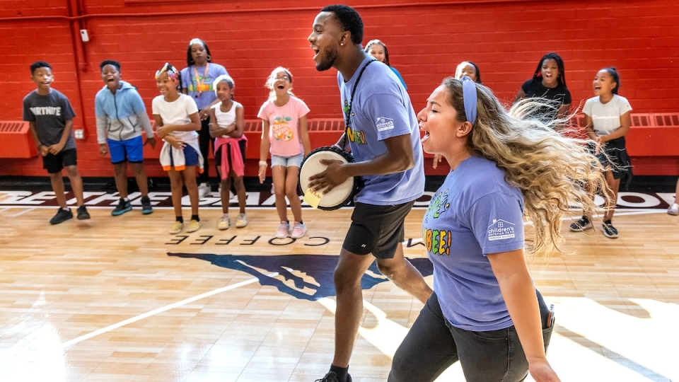 Students cheering while kids are in the background in a gym