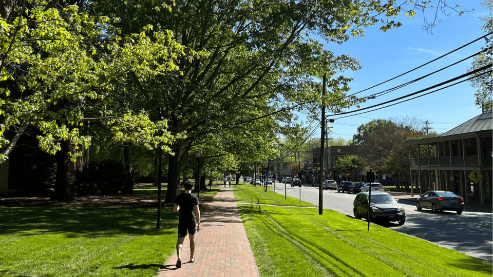 a student walks a brick sidewalk along a main street with blue skies in the background