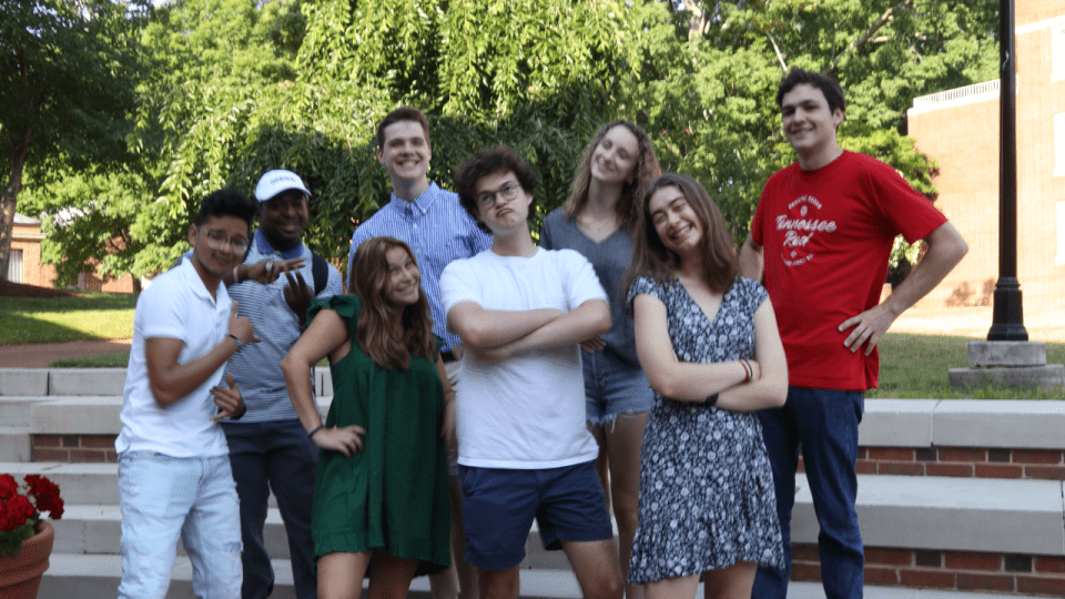 a group of students making silly faces while standing on stone steps outside