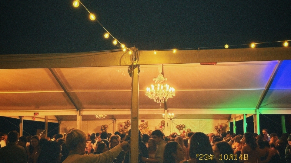 a tent covered in string lights at night and young people dancing underneath it