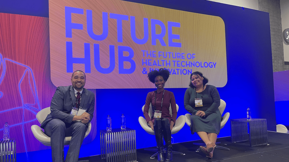 three young people sitting together in front of a sign that reads "Future Hub"