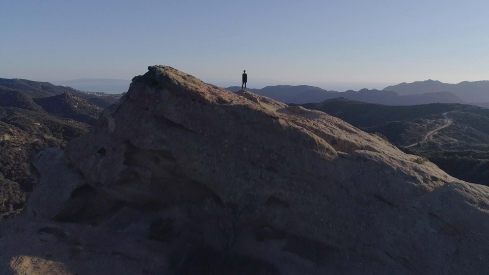 a figure stands on a mountain 