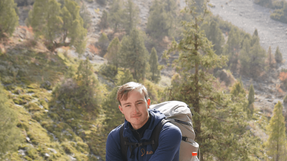 a young man stands in front of a valley