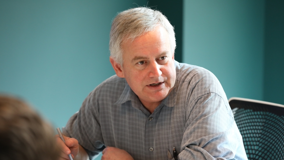 Prof Malcolm Campbell seated in conference room