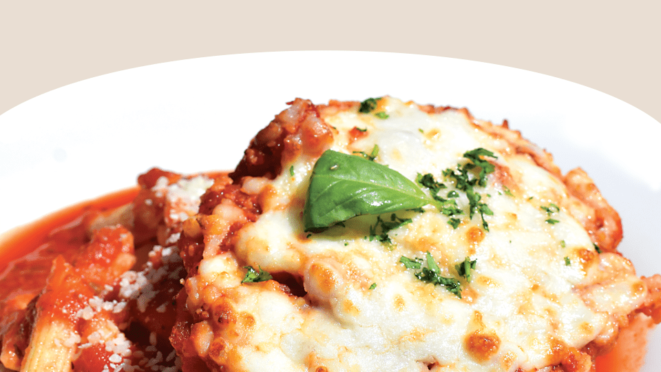 a plate of chicken parmesan on top of a plate of pasta and red sauce