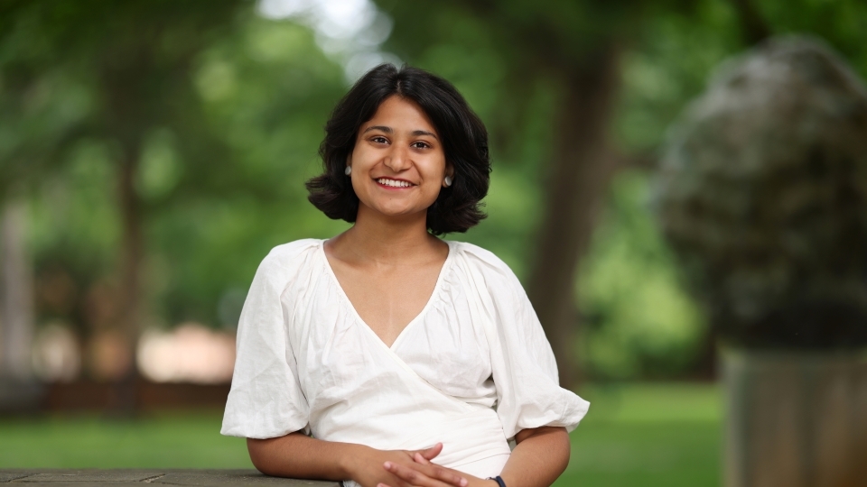 a young woman wearing white standing on a campus