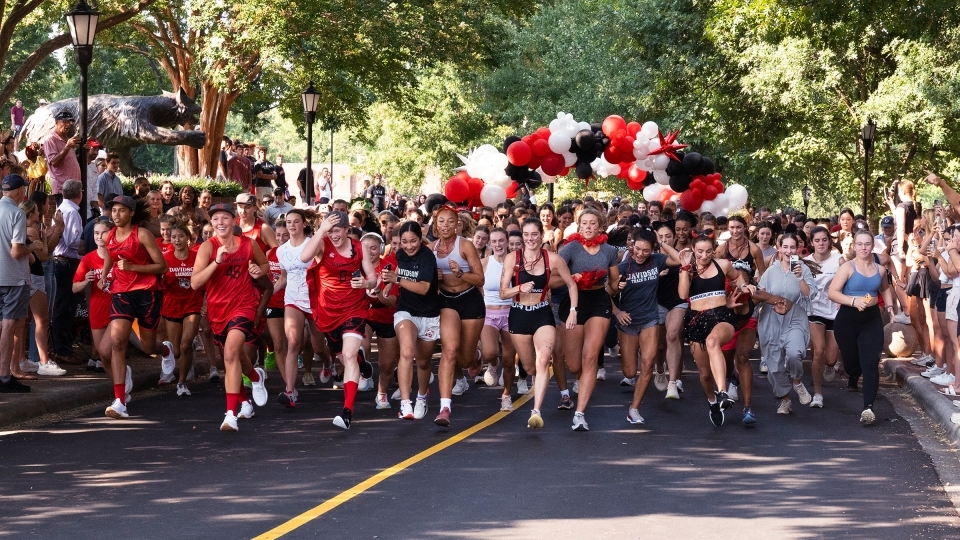 a group of young women run while smiling on a road