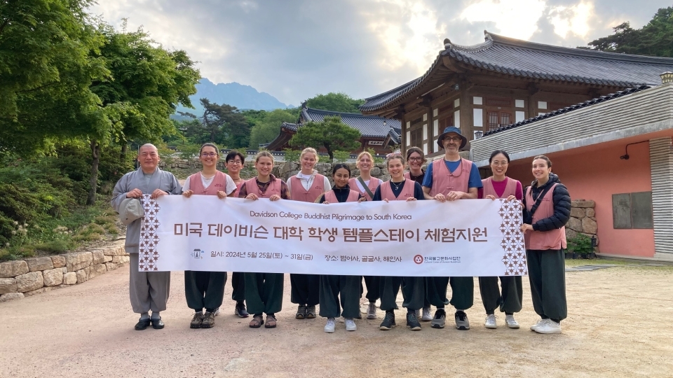 a group of students and adults standing together in front of a Buddhist temple