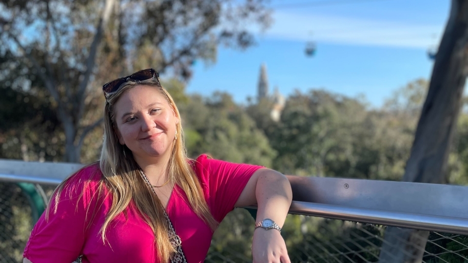 a young white woman stand on an outdoor balcony