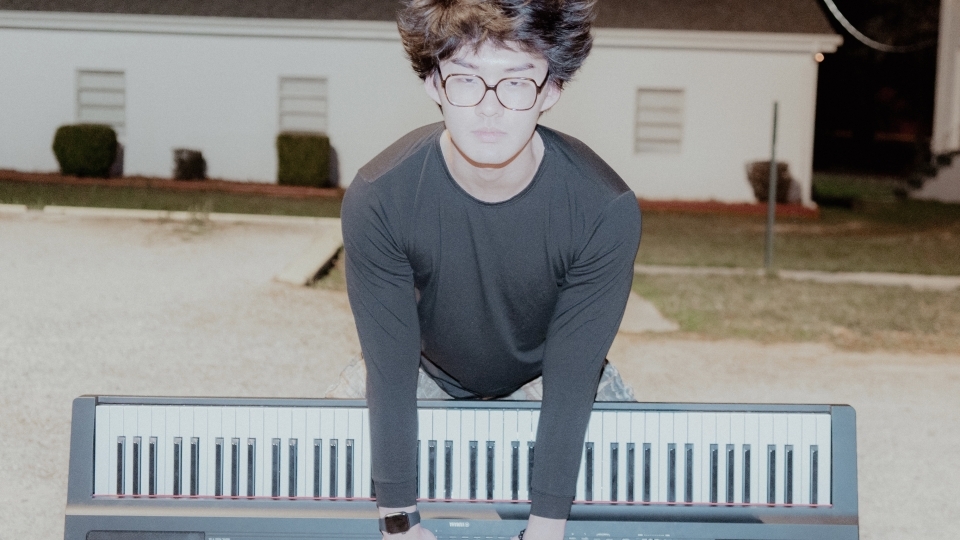 a young Asian man holding a piano