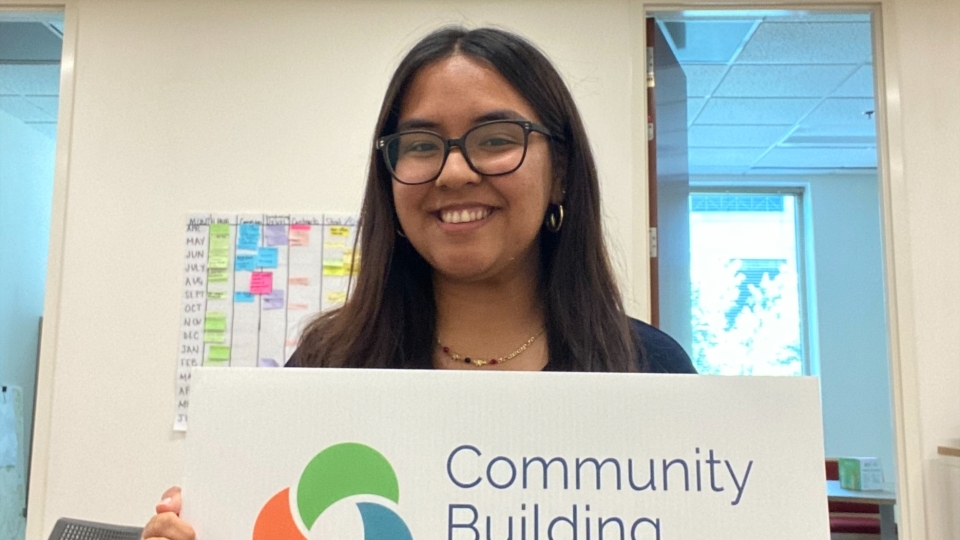 a young woman holds a sign that says "community building initiative"