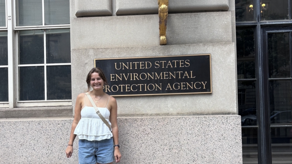 a young white woman stands in front of "US EPA" sign