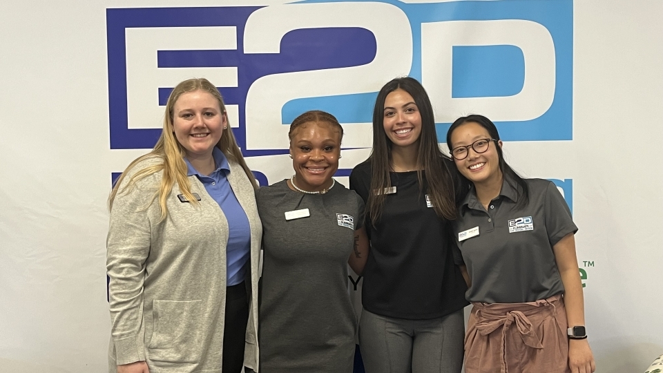 a group of young women standing in front of a wall that reads "E2D"