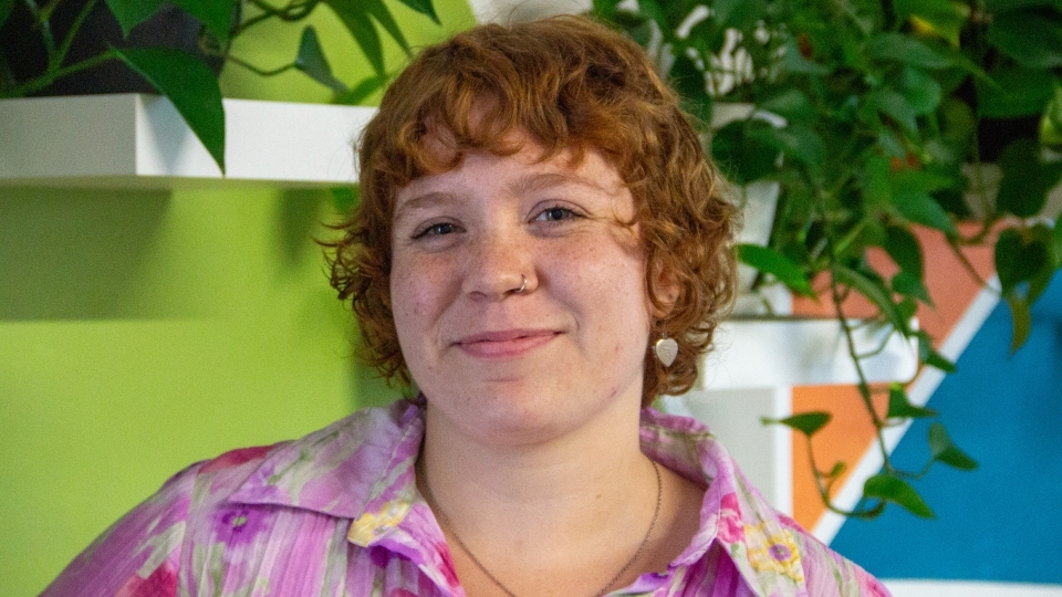 a young white woman with red hair wearing a pink top and smiling