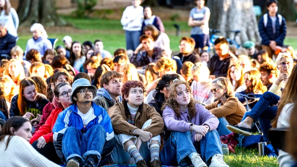 Students sit on the ground, listening intently, at the Phi Eu Debate