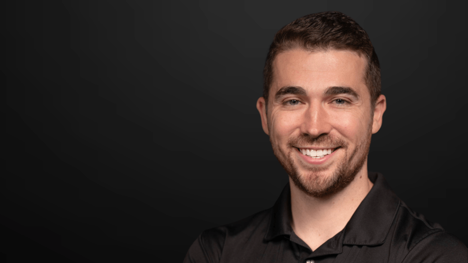 a young white man in a black polo smiling