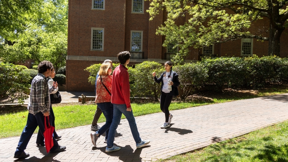 a young woman guides a family around a college campus