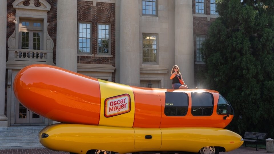 Emily Schmidtt '23 sits atop the Weinermobile in front of the Chambers Building