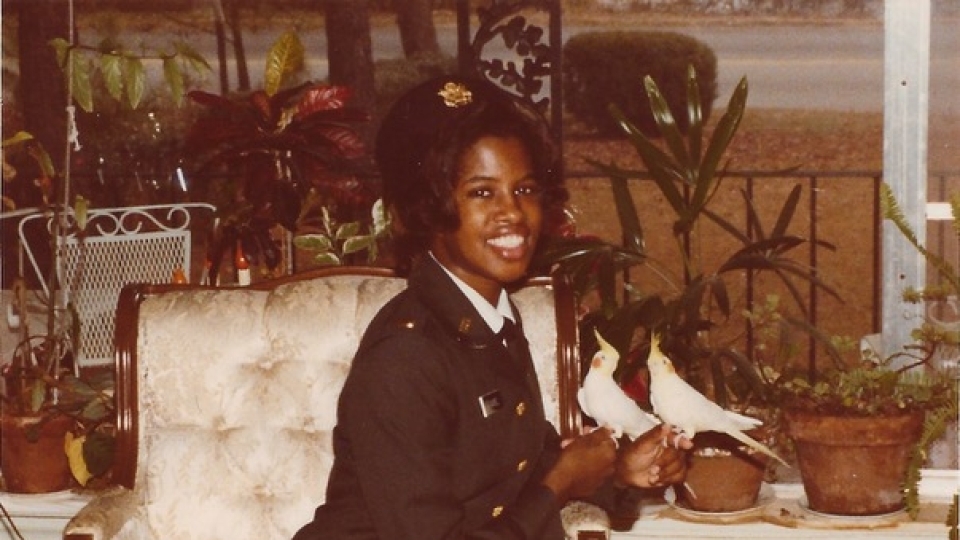 a young Black woman in uniform sitting on a white chair